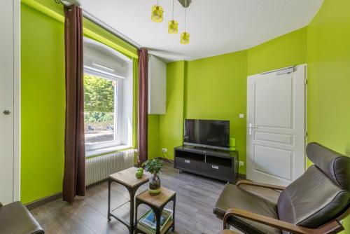 a living room with green walls and a television at Hôtel De La Plage in Le Chambon-sur-Lignon