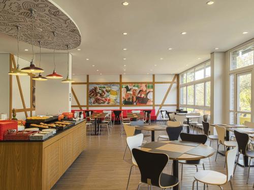 un restaurant avec des tables et des chaises et une cafétéria dans l'établissement ibis Igrejinha, à Igrejinha