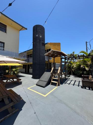 een patio met een speeltuin met bankjes en een gebouw bij Hostel Farol in Pontal do Paraná
