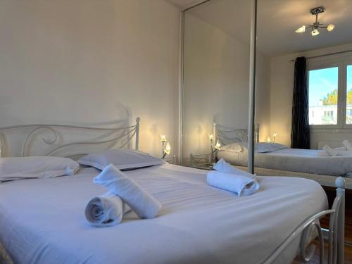 une chambre avec deux lits avec des draps blancs et des miroirs dans l'établissement Le 19 Lavigne - Parking, à Saint-Martin-dʼHères