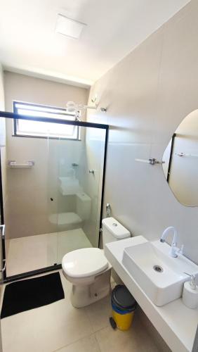 a bathroom with a toilet and a sink and a mirror at Mansão dos Mares 06 in Ilhéus