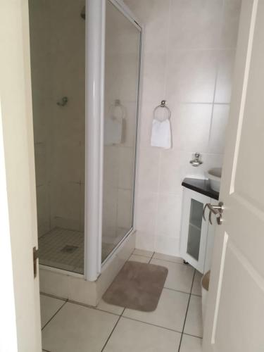 a white bathroom with a shower and a sink at 54 Topanga Holiday Accommodation in Margate