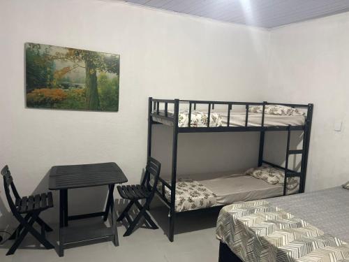 una camera con letto a castello, tavolo e letto di Kitnets Ubatumirim a Ubatuba