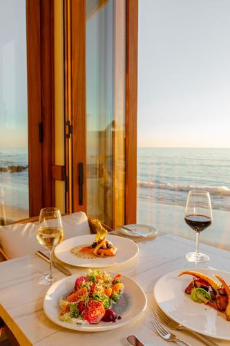 a table with two plates of food and glasses of wine at Surf & Sand Laguna Beach in Laguna Beach