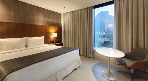 a hotel room with a large bed and a window at Hotel Nacional, Rio de Janeiro, Suíte Luxo com Banheira in Rio de Janeiro