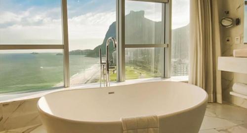 a bath tub in a bathroom with a large window at Hotel Nacional, Rio de Janeiro, Suíte Luxo com Banheira in Rio de Janeiro