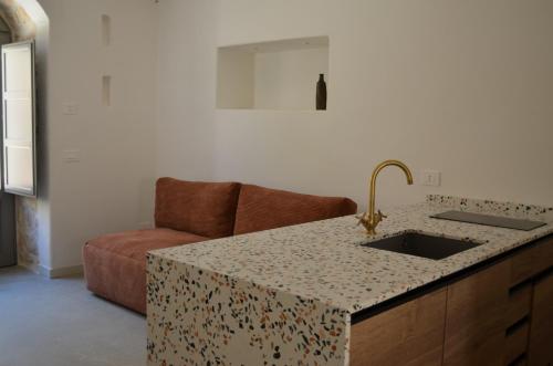 eine Küche mit einer Theke mit einer Spüle und einer Couch in der Unterkunft B&B Fuga al Trullo in Ostuni