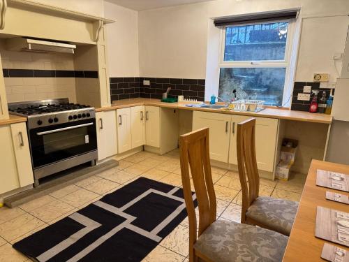 een keuken met een fornuis en een tafel met stoelen bij Sowerby Homes in Sowerby Bridge