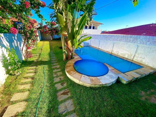 ein blauer Pool im Gras neben einer Mauer in der Unterkunft Casa 3 Quartos, 50 metros Da Praia in Cascavel