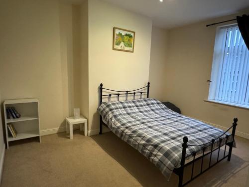 een slaapkamer met een bed met een geruite deken en een raam bij Sowerby Homes in Sowerby Bridge