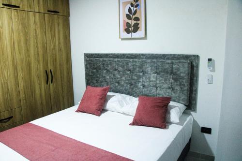 a bedroom with a bed with red and white pillows at Pura Vida in Quibdó