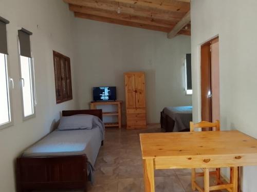 ein Schlafzimmer mit einem Bett und einem Tisch und einem Fernseher in der Unterkunft Tacuarita in Los Hornillos