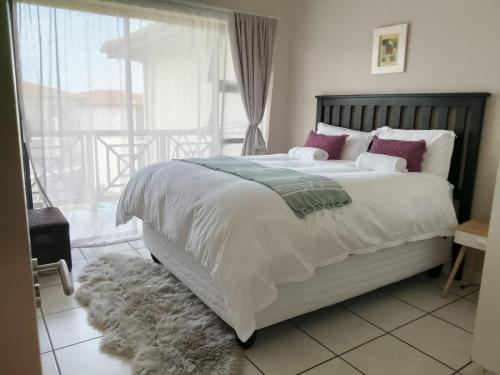 ein Schlafzimmer mit einem großen weißen Bett und einem Balkon in der Unterkunft 54 Topanga Holiday Accommodation in Margate