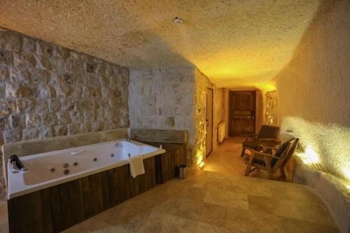 a bath tub in a room with a stone wall at Kayaharman cave otel in Nar