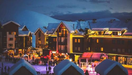 een groep gebouwen met mensen in de sneeuw 's nachts bij New Gudauri Redco Loft 1 in Goedaoeri