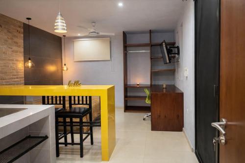 a kitchen with a yellow counter and a dining room at Minimalist City Suite - Plaza las Americas in Chetumal