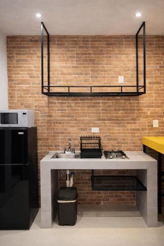 a kitchen with a sink and a brick wall at Minimalist City Suite - Plaza las Americas in Chetumal