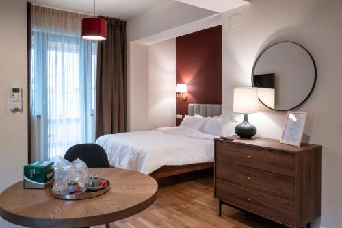 a hotel room with a bed and a table and a mirror at Habitat Suites - Modern Apartments with Terraces and Free Parking in Craiova