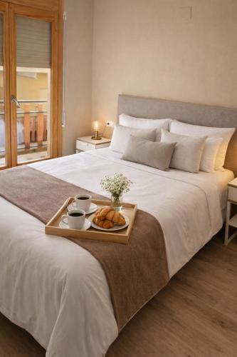a bed with a tray of bread and cups of coffee at CaL QuEROL Llivia 2 piscina, 8 pax, 2 baños y parking in Llivia
