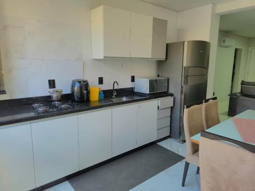 een keuken met witte kasten en een roestvrijstalen koelkast bij Ap Novo 303! Villa Premium in Piratuba