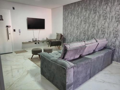 een woonkamer met een bank en een tv bij Ap Novo 303! Villa Premium in Piratuba