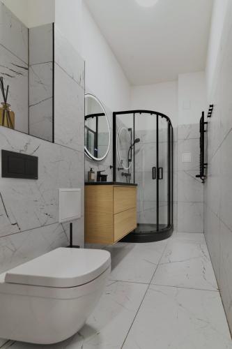 a white bathroom with a toilet and a mirror at MonjAna Premium Rynek in Wrocław