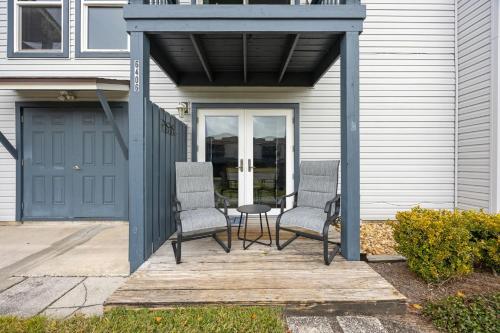 a porch with three chairs and a table and a door at Chill by The Shores - Pet Friendly - Fernandina Beach in Fernandina Beach