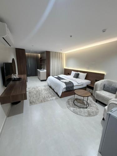 een slaapkamer met een bed, een bank en een stoel bij ديار الاسترخاء للشقق المخدومة in Najran