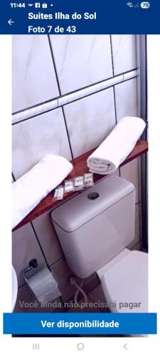 a bathroom with a toilet and a shelf with towels at Pousada Ilha do Sol in Cananéia