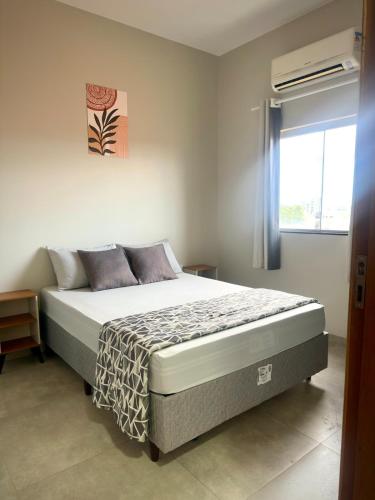 een slaapkamer met een bed in een kamer met een raam bij Apartamento Palmeira Essencial in Formosa