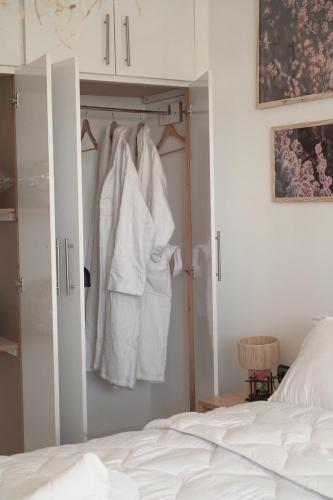 a bedroom with a bed and a closet with white clothes at Happiness Apartment in Ouarzazate