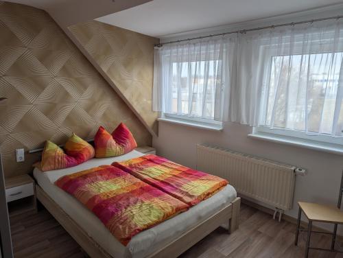 a bedroom with a bed with colorful blankets and pillows at Pension zum Ringelberg in Erfurt