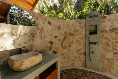 a bathroom with a stone wall with a stone sink at The Benison in Ahangama