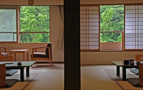 a room with tables and chairs and windows at Hotel Mahoroba in Noboribetsu