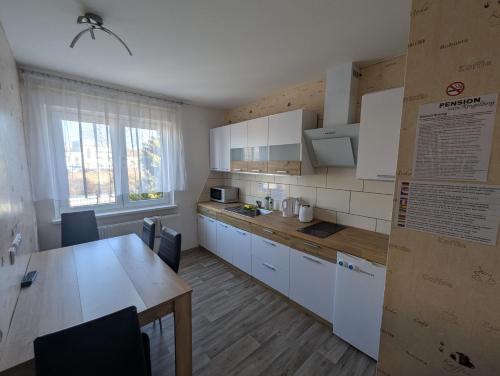 una cucina con mobili bianchi e un tavolo di legno di Pension zum Ringelberg a Erfurt