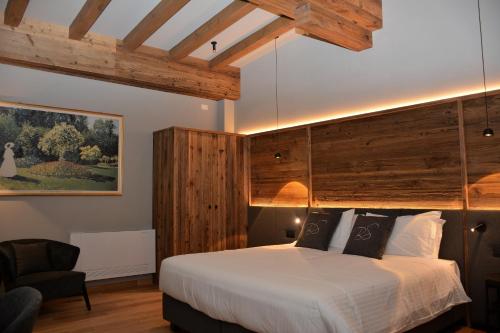 een slaapkamer met een groot bed en een stoel bij Hotel Bel Sit Wellness Spa in Valle di Cadore