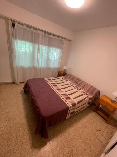 a bedroom with a bed and a window with a curtain at PH con cochera cubierta cerca de la playa in Villa Gesell