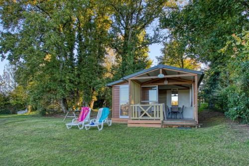 a small shed with two chairs in the grass at ZEcamping 3 étoiles familial do friendly piscine chauffée restaurant et bar in Les Eyzies-de-Tayac