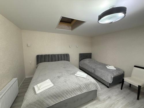 a bedroom with two beds and a lamp and a chair at Hotel Kalyan & Spa in Chişinău