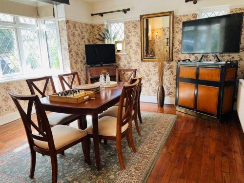ein Esszimmer mit Tisch und Stühlen und einem Fernseher in der Unterkunft The Norbury Hill Residence in West Norwood