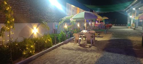 a patio with a table and an umbrella at night at Shiv Shakti Hotel And Resort in Mākundgarh