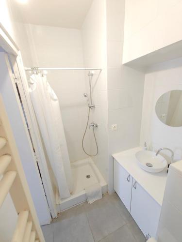 a white bathroom with a shower and a sink at L'Orangerie du Domaine F3 in Forges