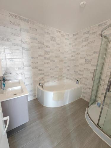 a bathroom with a tub and a sink at Le Grand Mauperthuis F4 in Forges
