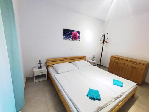 een slaapkamer met een bed met witte lakens en blauwe kussens bij Olcsica Apartment in Klenovica