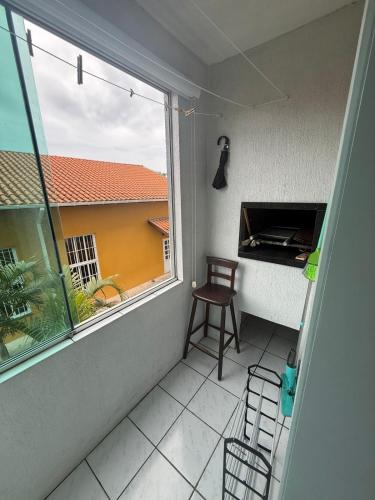 een leeg balkon met een stoel en een raam bij Apartamento inteiro 45m, centro, com garagem in Torres