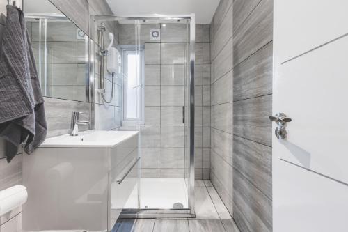 a white bathroom with a shower and a sink at Amazing serviced accommodations for Corporate Contractors and Leisure clients Located at a walking distance from three majors Underground and Overground stations in London