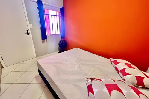 een bed in een kamer met een oranje muur bij Cantinho Perfeito Em Matinhos in Matinhos