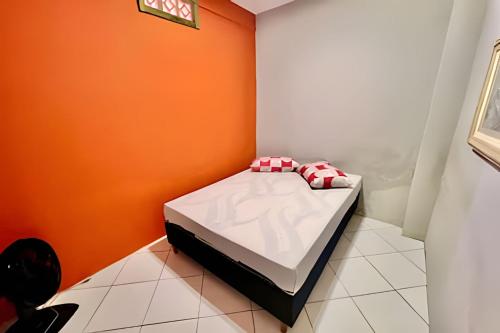 een kleine slaapkamer met een bed met een oranje muur bij Cantinho Perfeito Em Matinhos in Matinhos