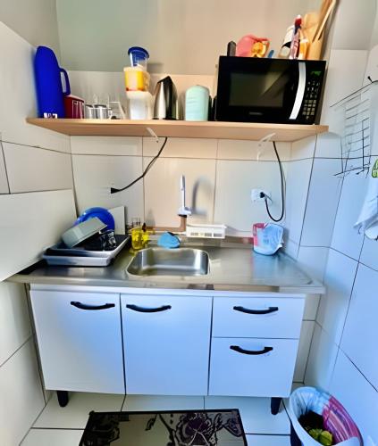 a small kitchen with a sink and a microwave at Cantinho Perfeito Em Matinhos in Matinhos