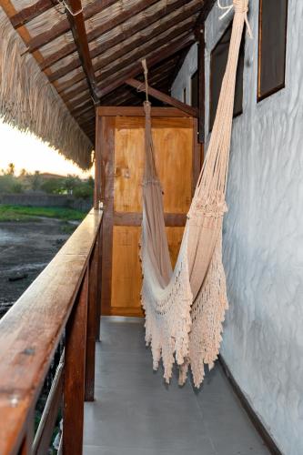 a hammock hanging on a porch with a door at Vila do Junco in Santo Amaro